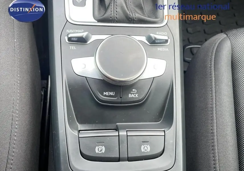 Gros plan sur la console centrale noire de l'Audi Q2 35 TFSI S-Line 2023, avec molette de contrôle et boutons de stationnement.