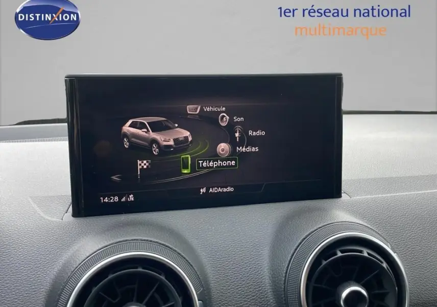 Écran central de l'Audi Q2 35 TFSI S-Line 2023 affichant le menu téléphone, avec aérateurs ronds en avant-plan.