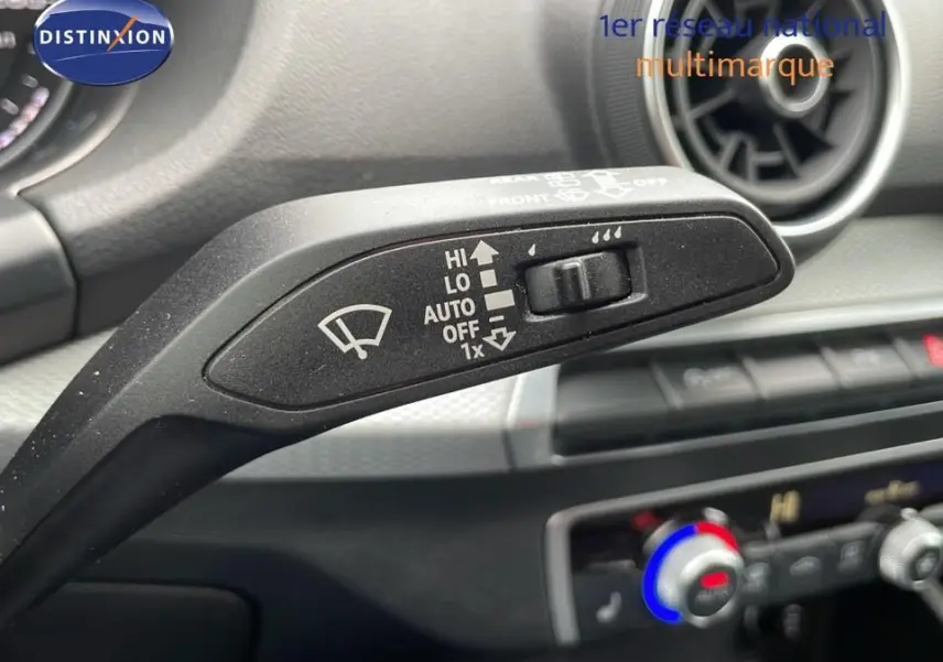 Gros plan sur la commande d'essuie-glace gauche de l'Audi Q2 noir mito metal, avec tableau de bord et aérateur en arrière-plan.