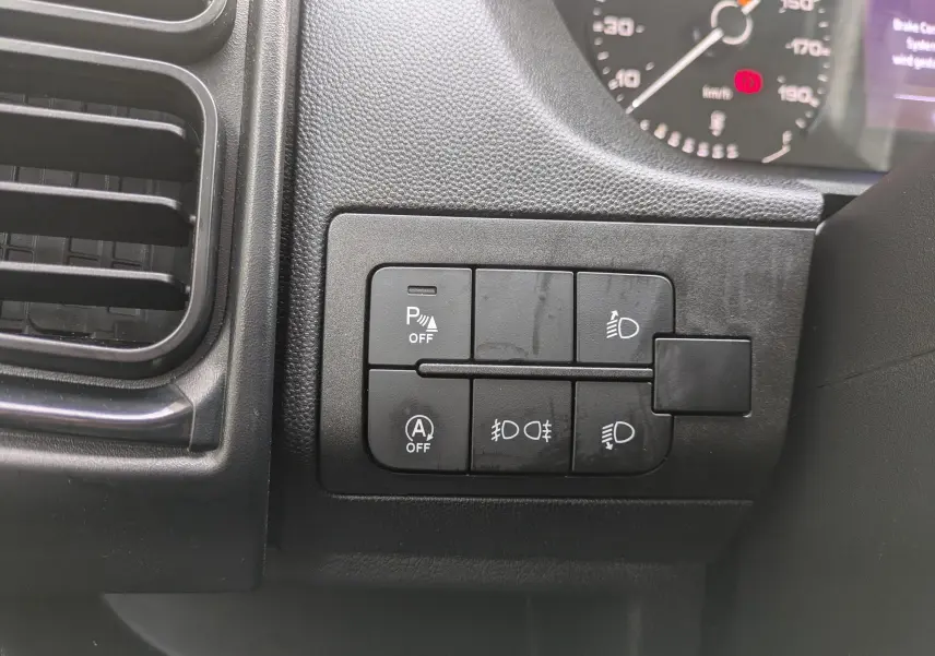 Boutons de commande des feux et aides à la conduite sur tableau de bord noir du Peugeot Boxer Fourgon blanc 2025.