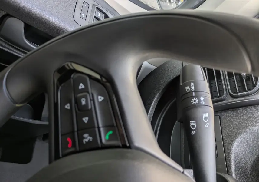 Vue intérieure rapprochée du volant et commande de phares du Peugeot Boxer Fourgon blanc, avec rétroviseur extérieur visible.