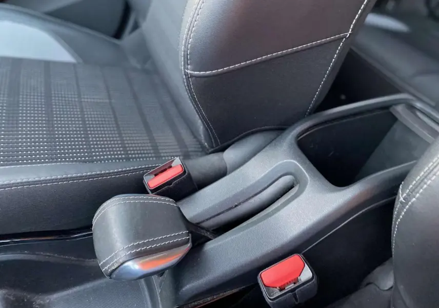 Gros plan sur le frein à main type aviation et les sièges sport noirs avec surpiqûres blanches du Peugeot 2008 noir Perla Nera.