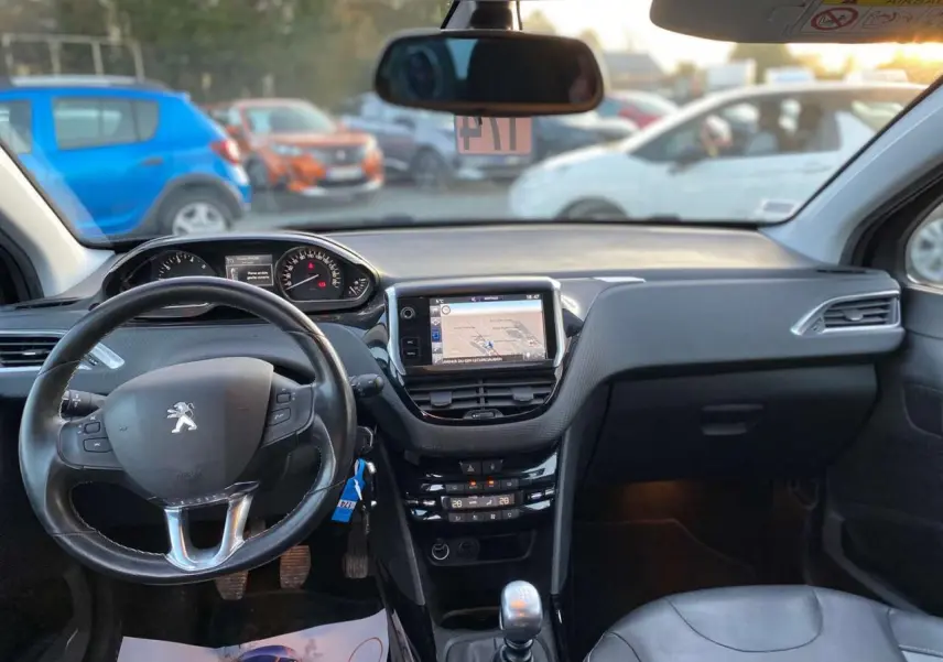 Vue intérieure avant du Peugeot 2008 noir Perla Nera de 2017, avec volant sport, écran tactile et boîte manuelle.