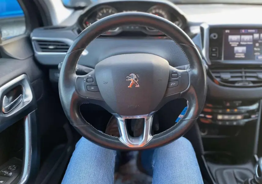 Vue intérieure centrée sur le volant cuir noir du Peugeot 2008 avec tableau de bord et écran tactile visibles.
