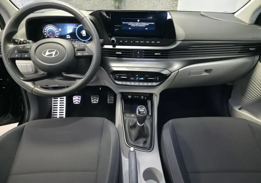 Vue intérieure avant du Hyundai Bayon 2025 noir, volant cuir, écran tactile 10,25'', boîte manuelle et console centrale épurée.