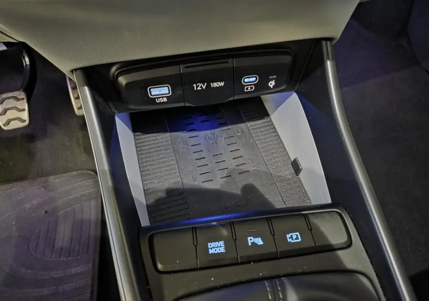 Gros plan sur la console centrale noire du Hyundai Bayon 2025, avec chargeur sans fil et commandes de stationnement.