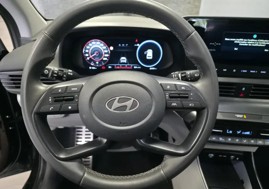 Vue rapprochée du volant cuir noir de la Hyundai Bayon 2025 avec tableau de bord numérique et écran tactile.