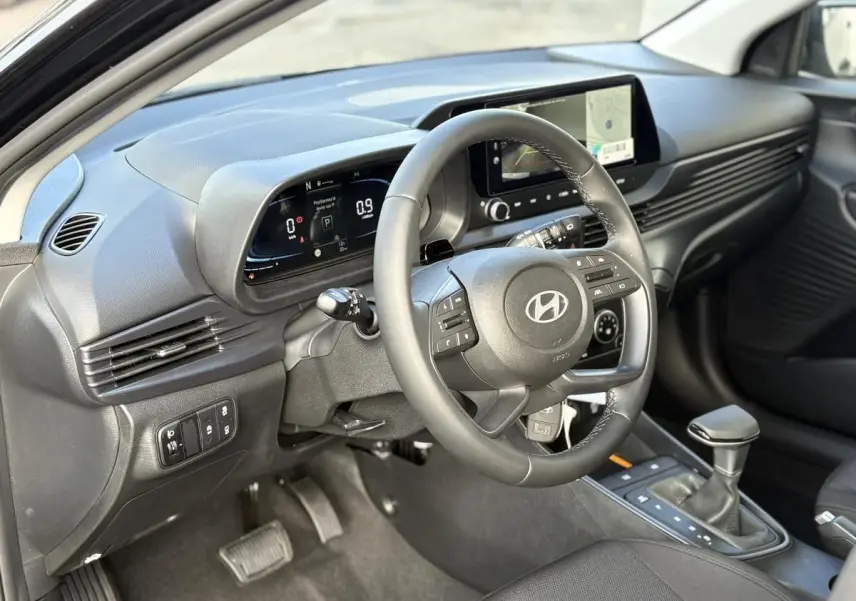 Vue intérieure côté conducteur de la Hyundai i20 2026 noir métal, avec tableau de bord digital et volant multifonction.
