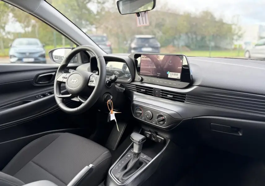 Vue intérieure côté conducteur de la Hyundai i20 2026 noire métal, avec tableau de bord moderne et écran tactile central.