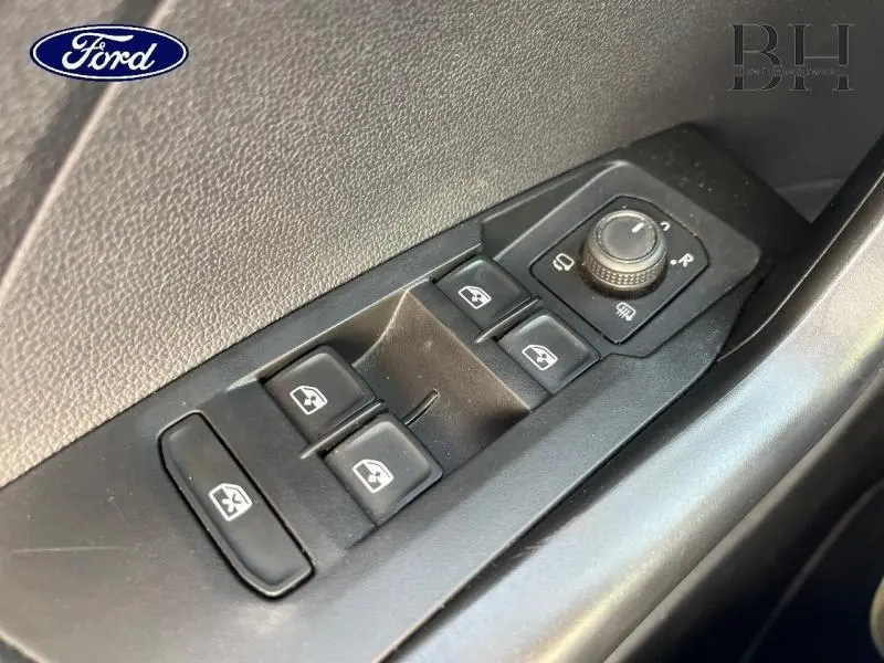 Gros plan sur les commandes des vitres et rétroviseurs côté conducteur d'un Volkswagen T-cross gris cendré.