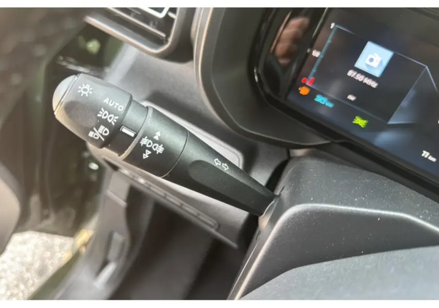 Gros plan sur la manette des feux et clignotants du Citroën Berlingo 2025, intérieur noir avec combiné numérique.