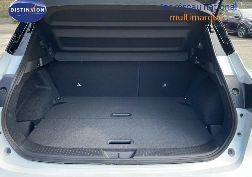 Coffre ouvert vu de l'arrière d'un Nissan Qashqai blanc nacré avec toit noir, montrant un espace de chargement plat et spacieux.