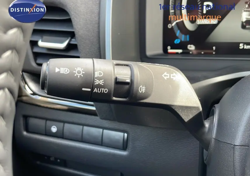 Gros plan sur la manette de commande des phares et clignotants dans l'habitacle du Nissan Qashqai blanc nacré 2025.