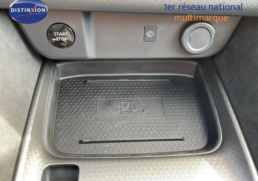Gros plan sur la console centrale du Nissan Qashqai blanc nacré, montrant le bouton Start/Stop et le chargeur sans fil.