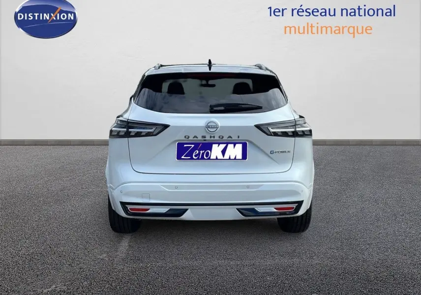 Vue arrière d'un Nissan Qashqai blanc nacré avec toit noir, version hybride e-power 2025, sur fond neutre.