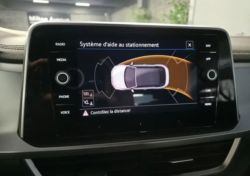 Écran tactile du système d'aide au stationnement du Volkswagen T-Roc 2024, affichage vue dessus du véhicule blanc.