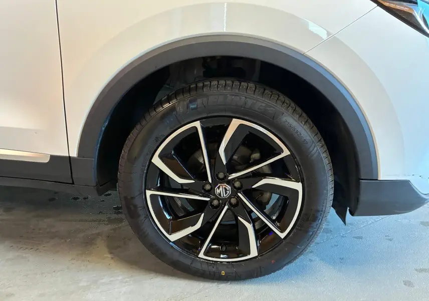 Gros plan sur la roue avant droite du MG ZS blanc 2022, mettant en valeur la jante noire et argentée au design moderne.