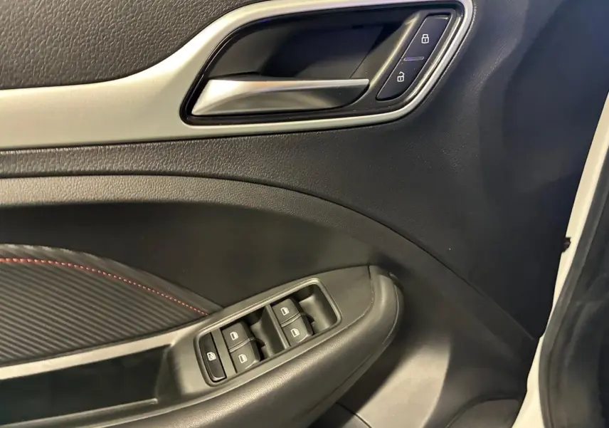 Gros plan sur la porte intérieure côté gauche du MG ZS blanc, avec commandes de vitres et verrouillage visibles.