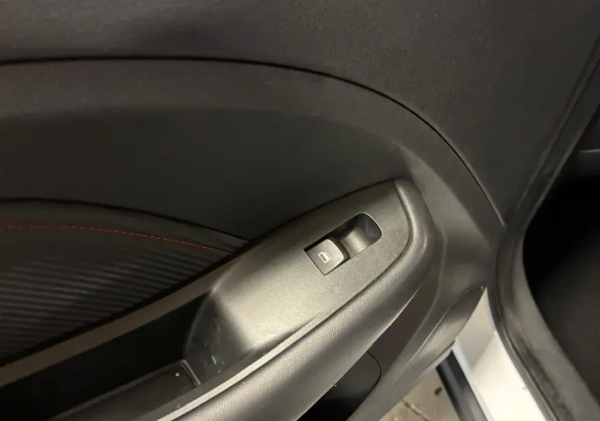 Gros plan sur le bouton de commande de la vitre électrique côté conducteur d’un MG ZS blanc, intérieur noir.