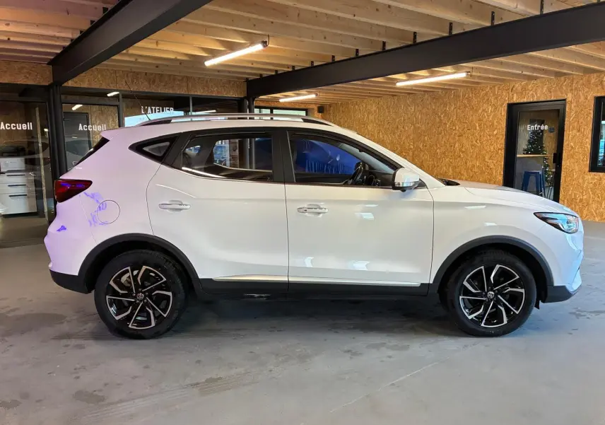 Vue de profil côté gauche du SUV blanc MG ZS 2022 avec jantes alliage noires et intérieur visible.