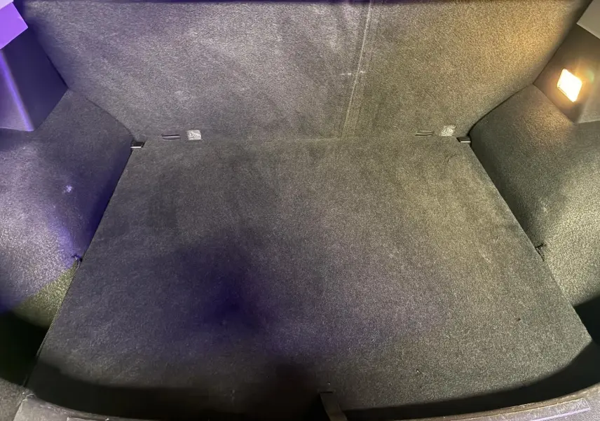 Vue intérieure du coffre spacieux et propre du MG ZS blanc, éclairé par une lampe intégrée sur le côté droit.