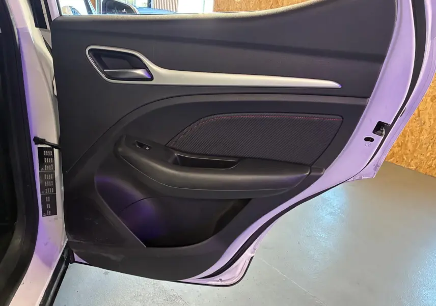 Vue intérieure de la porte arrière droite blanche du MG ZS 2022 avec garniture noire et surpiqûres rouges.