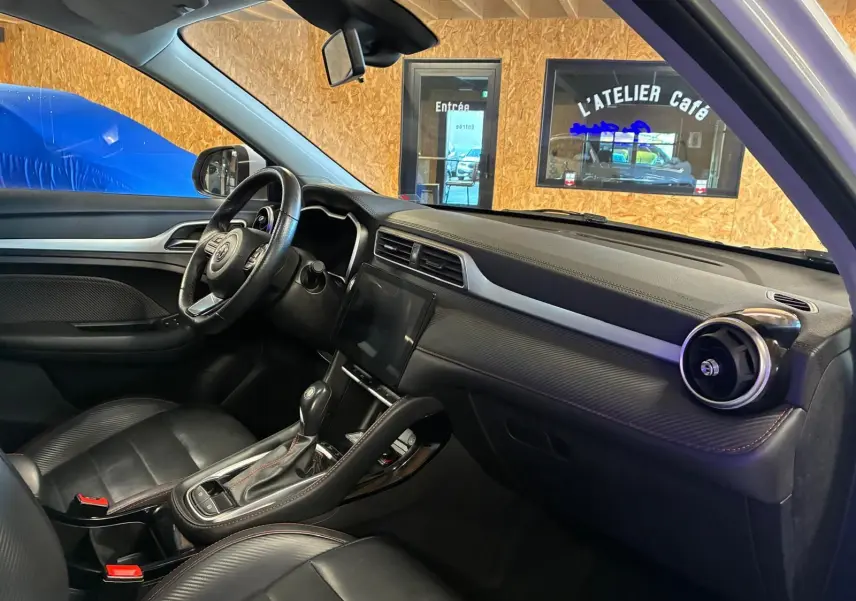 Vue intérieure côté conducteur du MG ZS 1.0 TGDI 111 BVA Luxury 2022 avec sellerie cuir noire et tableau de bord moderne.
