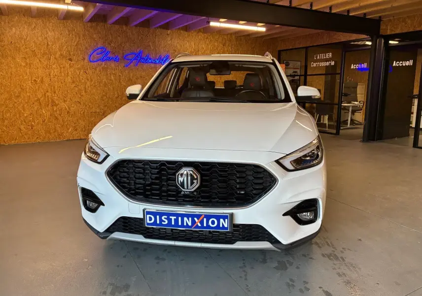 Vue avant d’un MG ZS blanc 2022 en showroom, avec calandre noire et logo MG bien visible.