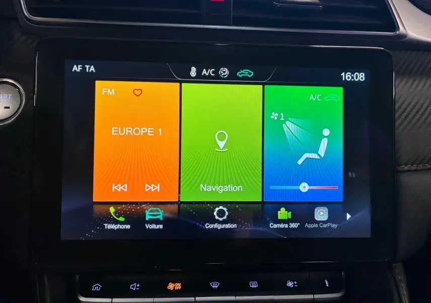 Écran tactile central de la MG ZS 2022, affichant radio, navigation et commandes climatisation, intérieur noir avec détails rouges.