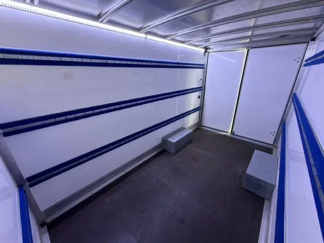 Intérieur du coffre blanc du Renault Master 2023, vue en plongée montrant les parois avec rails bleus et plancher noir.