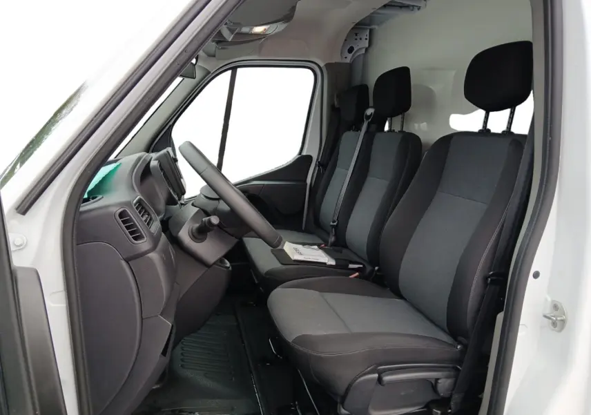 Vue intérieure côté conducteur du Renault Master blanc 2023, montrant les sièges avant en tissu gris et noir.