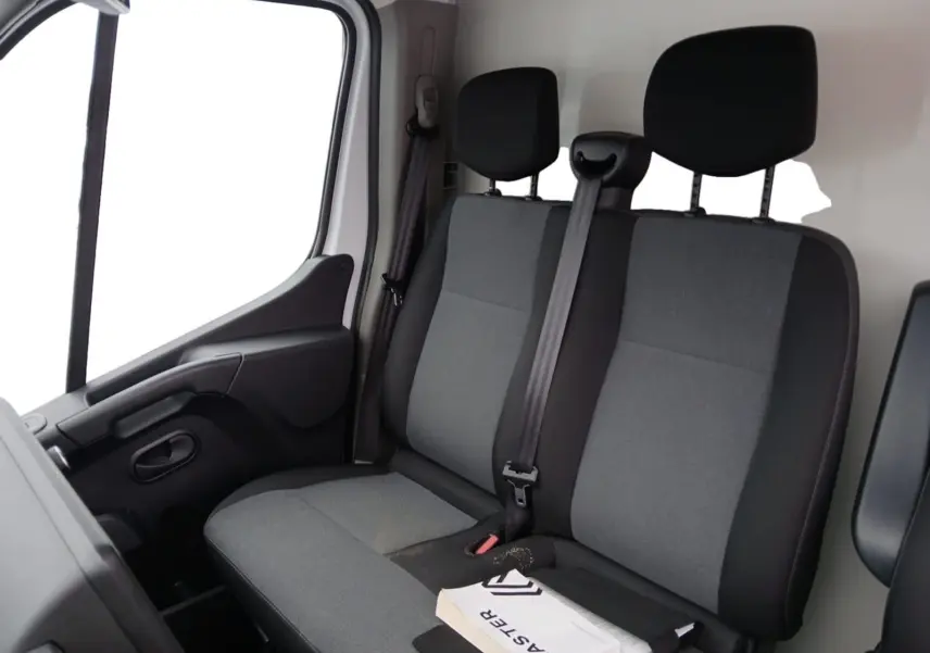 Vue intérieure côté passager montrant la banquette grise et noire du Renault Master 2023 avec un manuel posé dessus.