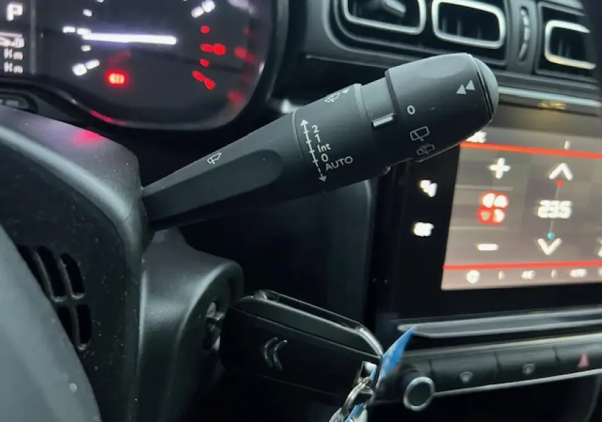 Gros plan sur la commande d’essuie-glace et le tableau de bord numérique d’une Citroën C3 Shine 2023 essence, intérieur noir.