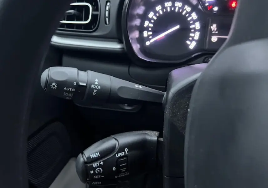 Détail intérieur du tableau de bord de Citroën C3 Shine 2023, montrant les commandes au volant et le compteur lumineux.