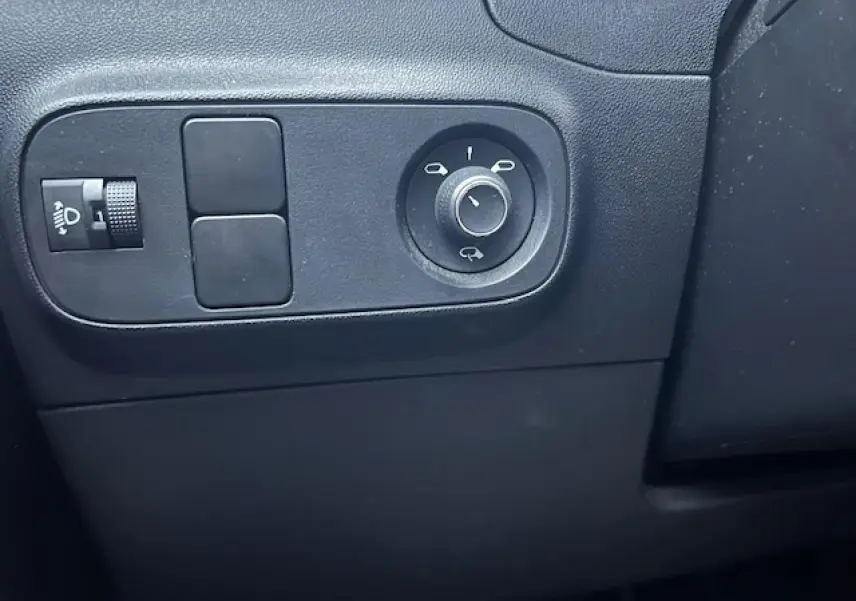 Détail des commandes de réglage des rétroviseurs et de l'éclairage sur la planche de bord noire d'une Citroën C3 Shine 2023.