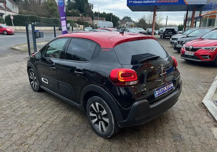 Vue 3/4 arrière droite d'une Citroën C3 Shine 2023 noire avec toit rouge et jantes alliage diamantées.