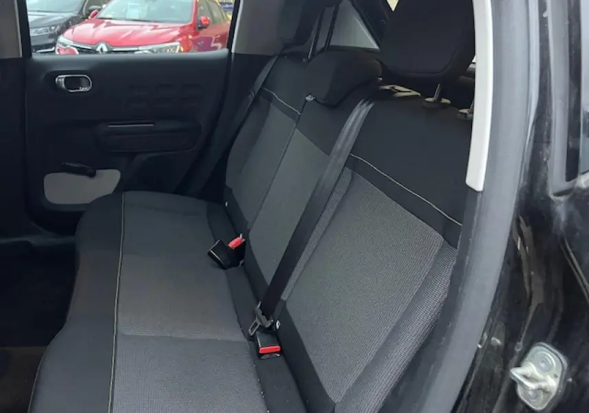 Vue intérieure côté droit sur la banquette arrière noire et grise d'une Citroën C3 Shine 2023 toit rouge visible partiellement.