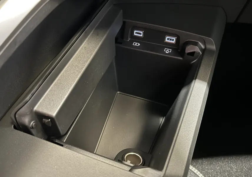 Gros plan sur la console centrale noire du Peugeot 3008 Hybrid avec ports USB et prise 12V visibles.