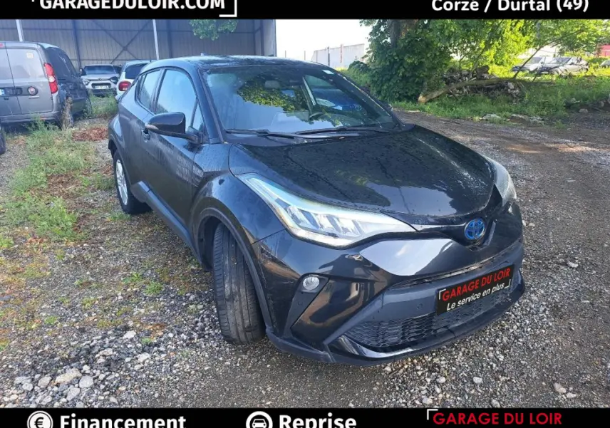 Toyota C-HR noir vue 3/4 avant droit sur terrain gravillonné avec calandre et phares LED distinctifs.