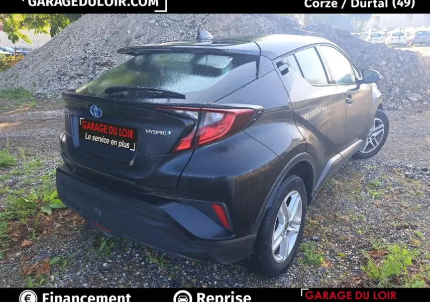 Vue 3/4 arrière droite d'un Toyota C-HR hybride noir avec feux arrière LED et toit avec aileron.