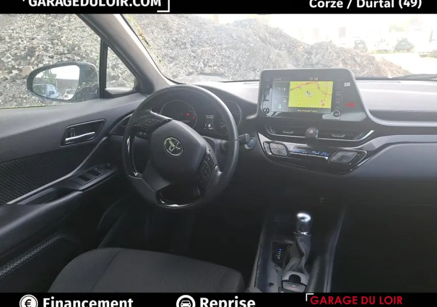 Vue intérieure côté conducteur du tableau de bord noir du Toyota C-HR 1.8 Hybride avec écran tactile et volant multifonctions.