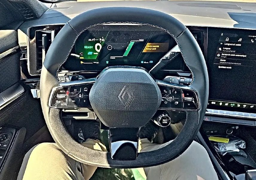 Vue intérieure centrée sur le volant multifonction du Renault Austral blanc nacré avec écran numérique en arrière-plan.