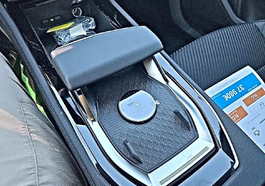 Gros plan sur l'accoudoir central et la console noire brillante du Renault Austral 2026, intérieur tissu carbone.