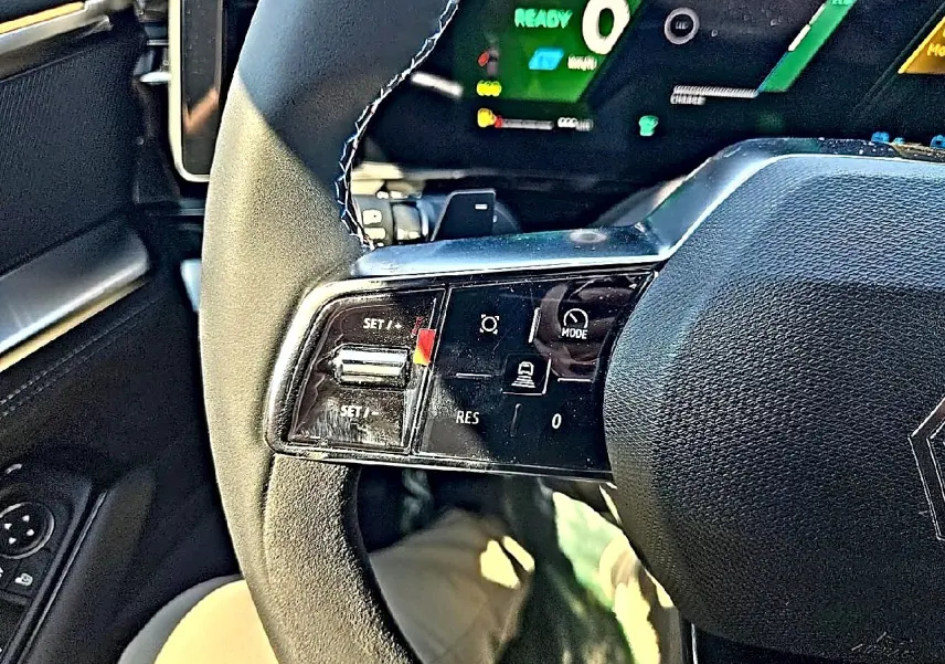 Gros plan sur le volant noir multifonction du Renault Austral blanc nacré, avec commandes de régulateur de vitesse visibles.