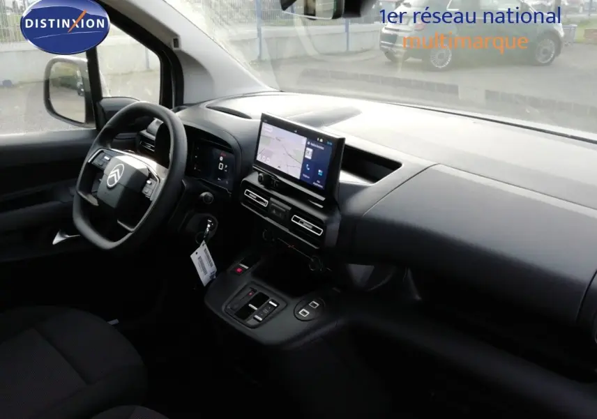 Intérieur du Citroën Berlingo XL 2026 vu côté conducteur, tableau de bord noir avec écran tactile central allumé.