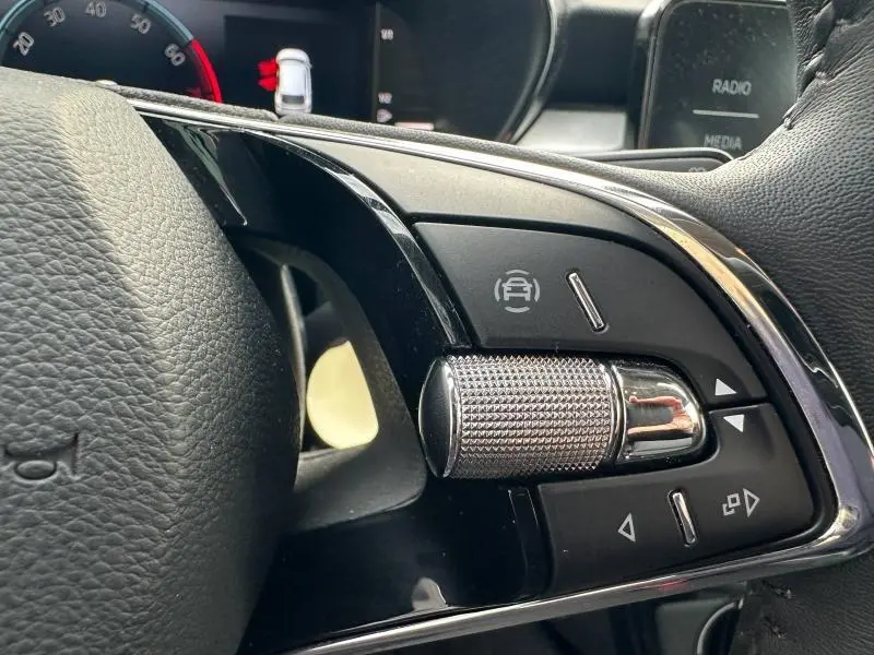 Gros plan sur les commandes de régulateur de vitesse au volant cuir noir de la Skoda Fabia bleu 2024