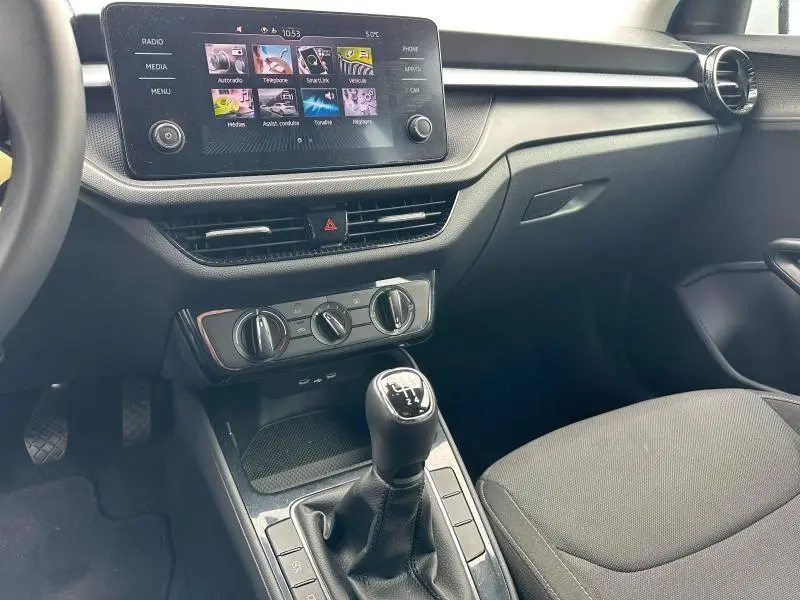 Intérieur de la Skoda Fabia 2024 bleu, vue côté passager montrant la console centrale avec écran tactile et levier de vitesse manuel.