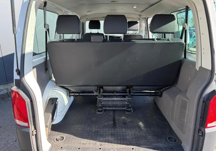 Vue arrière du Volkswagen Transporter T6 blanc, coffre ouvert montrant la banquette arrière et l'espace de chargement.