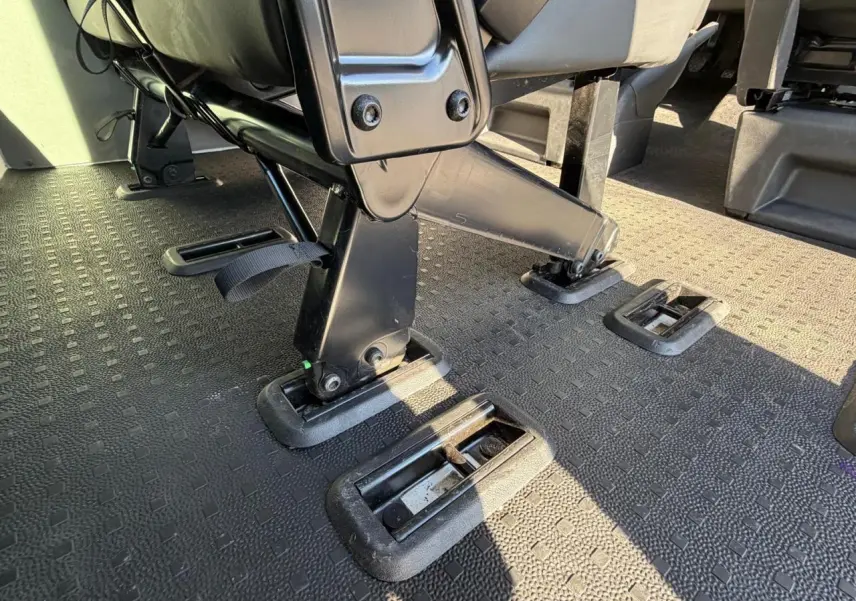 Gros plan sur le système d'ancrage des sièges noirs dans l'habitacle du Volkswagen Transporter T6 blanc.