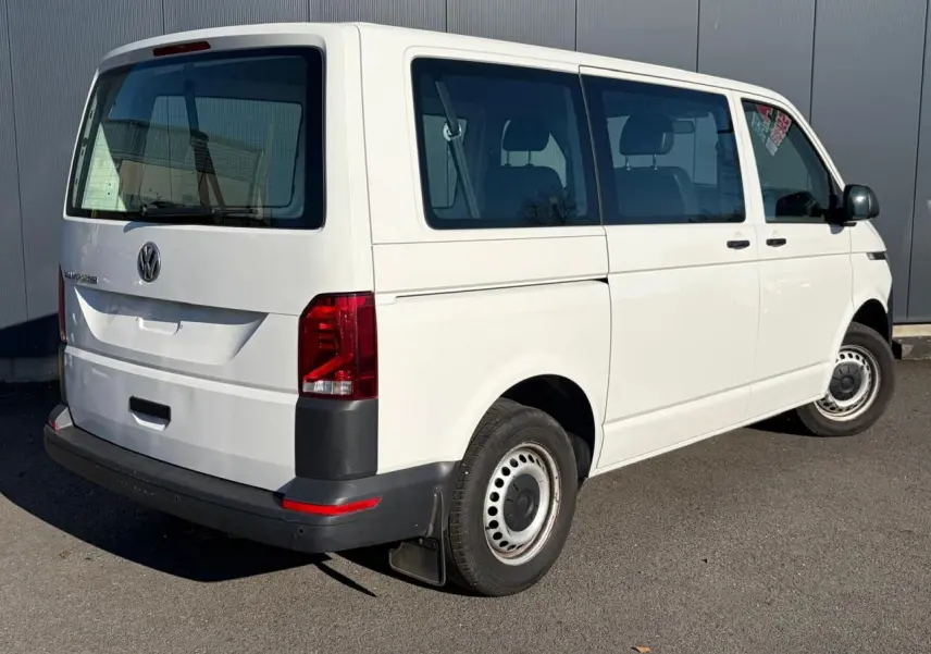 Vue 3/4 arrière droite d’un Volkswagen Transporter T6 Minibus blanc, avec porte coulissante et jantes acier.